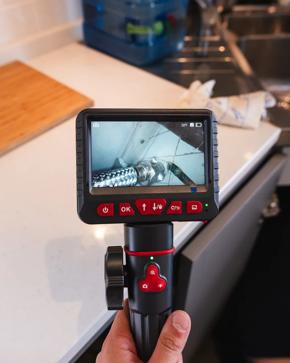 Inspection camera screen showing pipe connections in a concealed space